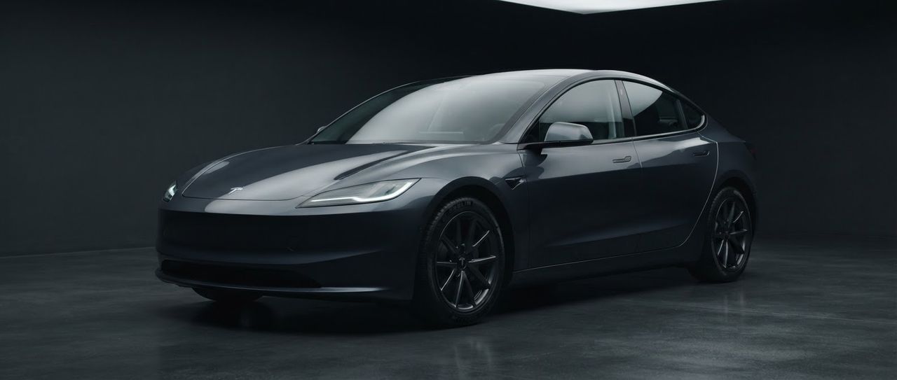 A dark grey Tesla Model 3, photographed side-on